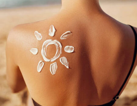 Skin care. Sun protection. Woman apply sun cream. Woman With Suntan Lotion On Beach In Form Of The Sun. Portrait Of Female With  Drawn Sun On A Shoulder. Suncream. Girl Holding Moisturizing Sunblock.